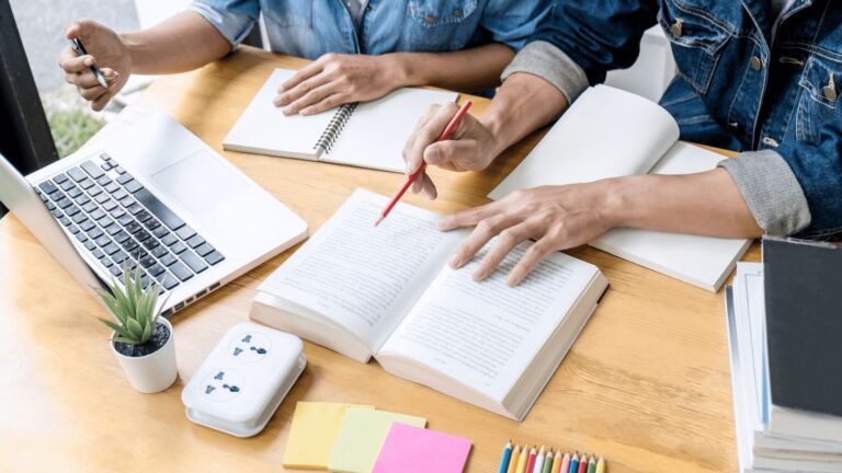 Cluttered desk with laptop and books.